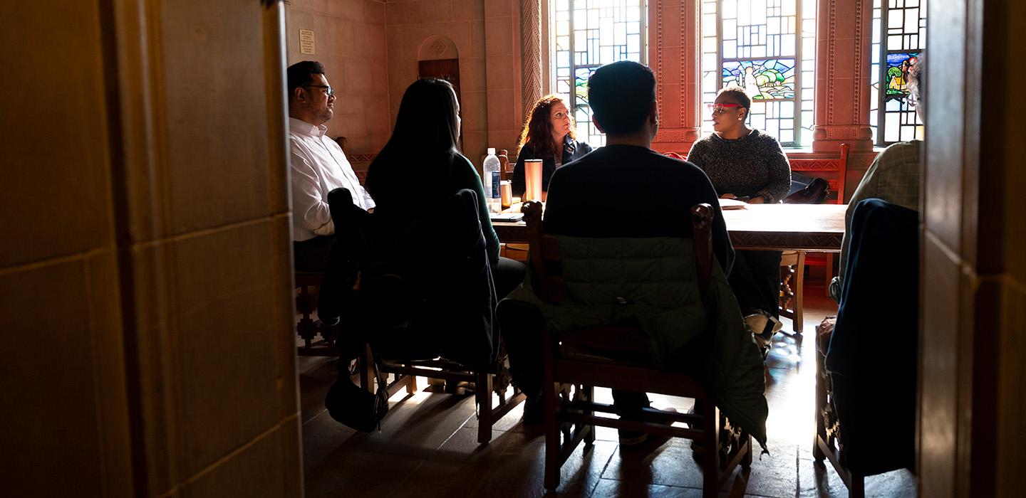 People sit around a table in a room with stained glass windows