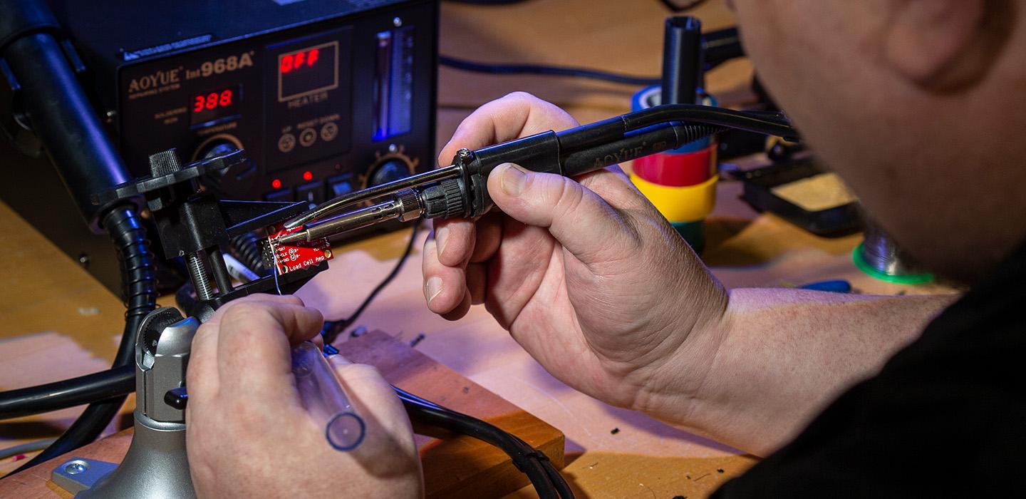 A person uses tools on a small metal chip