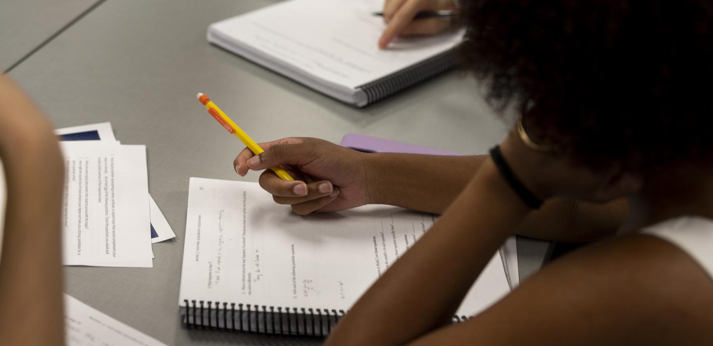 Student holding a pencil and looking at a notebook