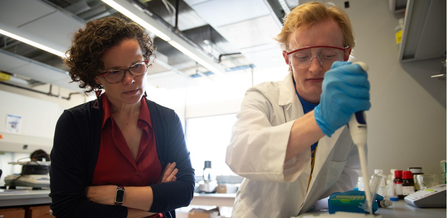 Carla Ng watches a student pipette in the lab