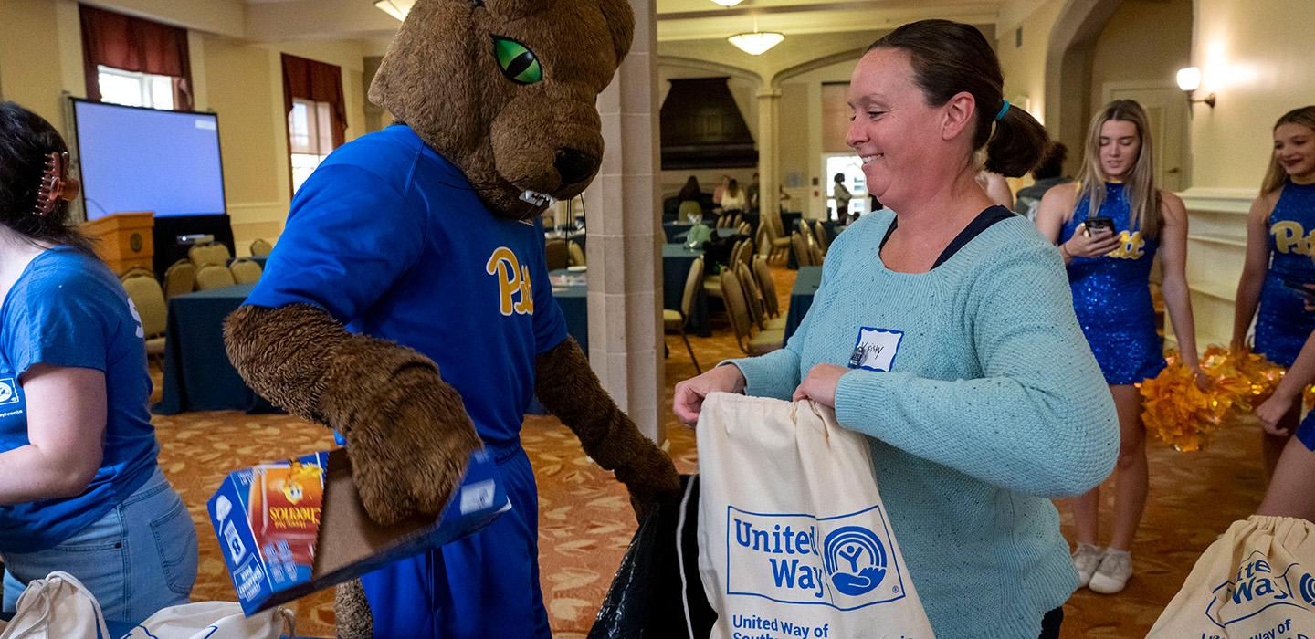 ROC packs cereal into a United Way bag, held by a volunteer