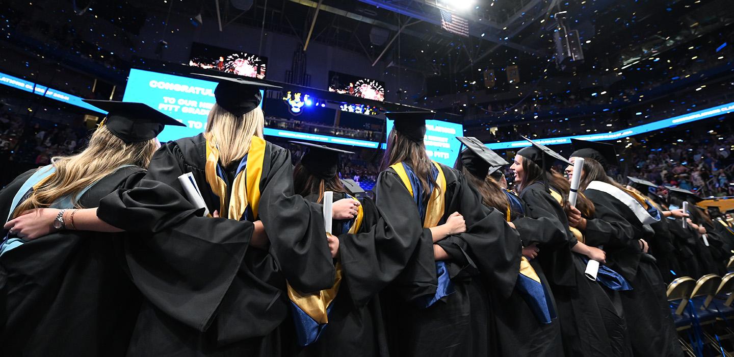 Graduates link arms after the ceremony