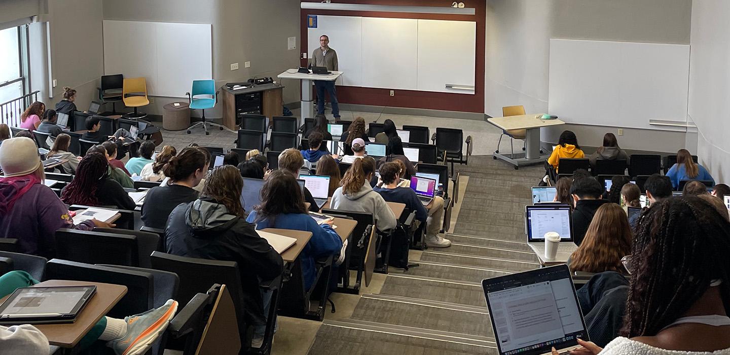 Students taking notes in a large lecture hall 