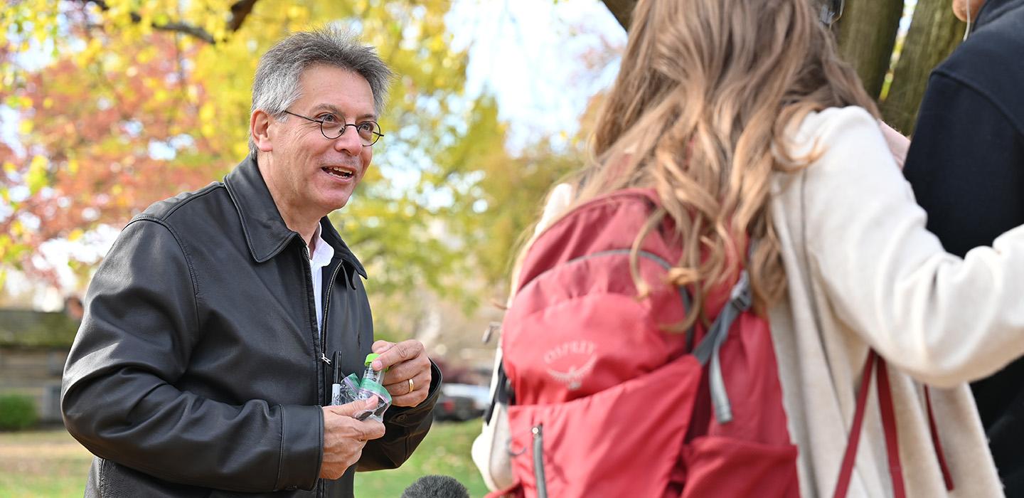 Hatfull holds sample bottles while speaking to a camera crew