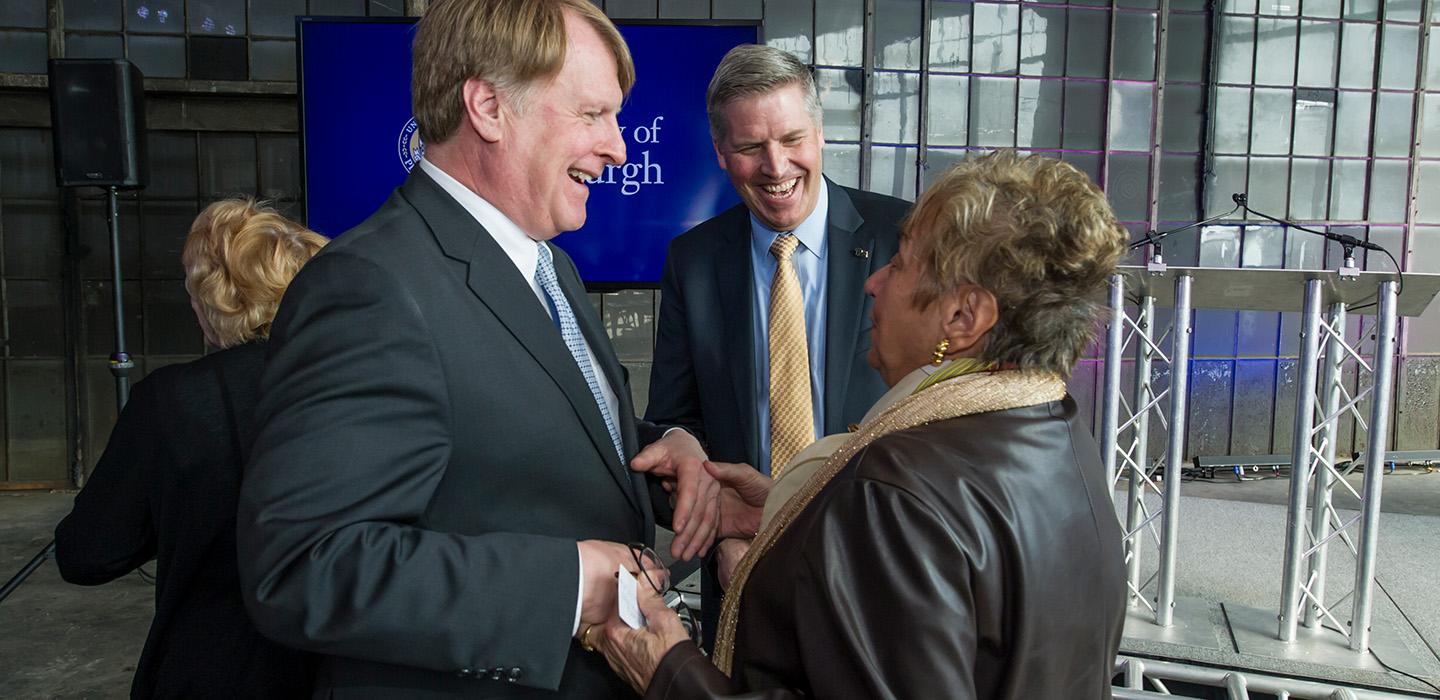Chancellor Gallagher looks on as two people shake hands