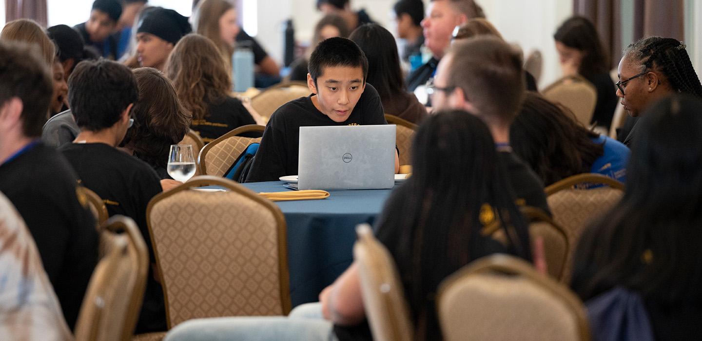 A high school student focuses on their laptop during Pitt's CyberCamp.