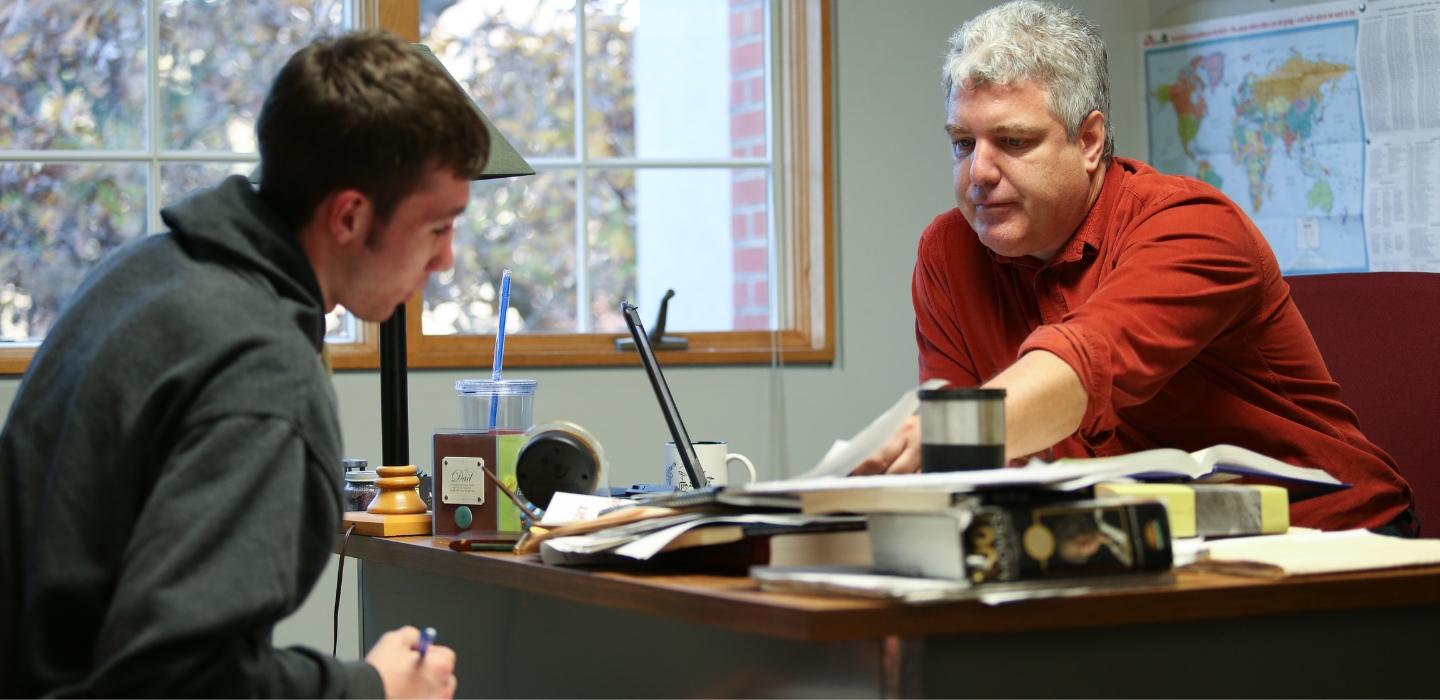 A professor helps a student during office hours.