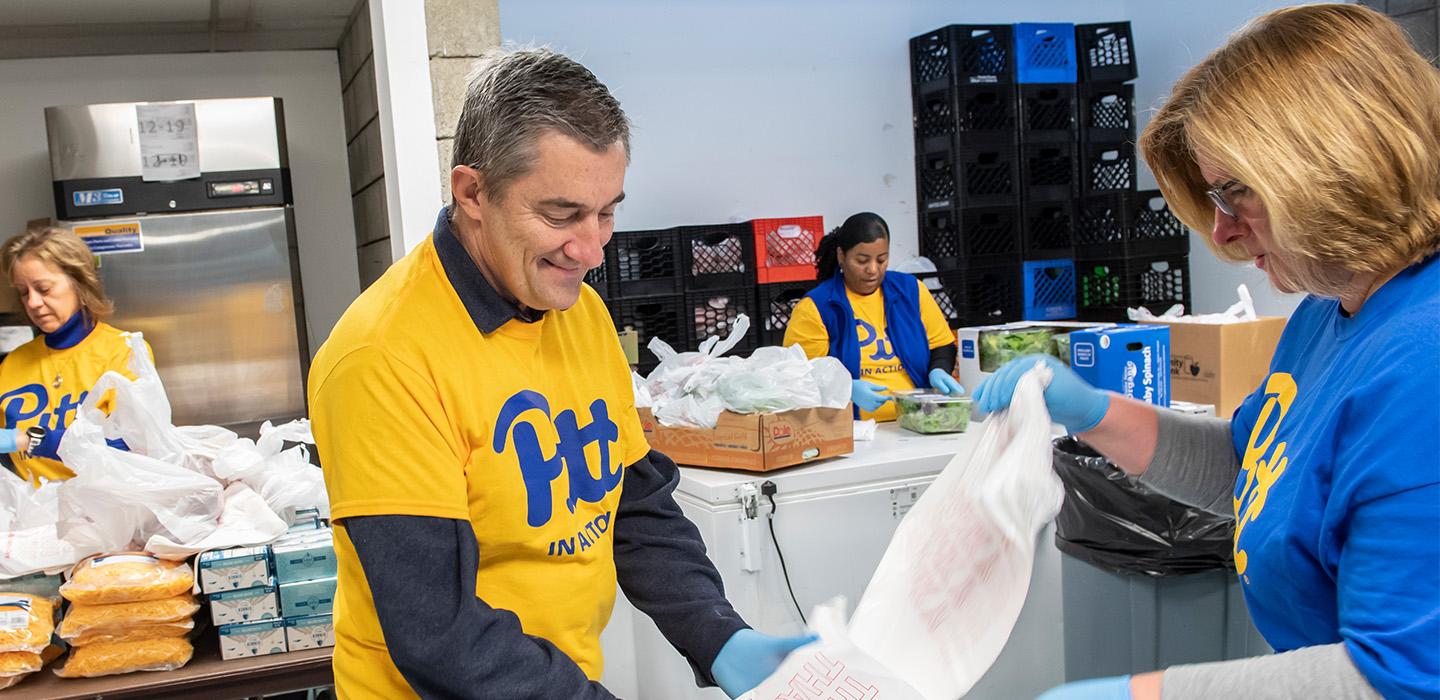 Volunteers wearing Pitt t-shirts pack bags of supplies