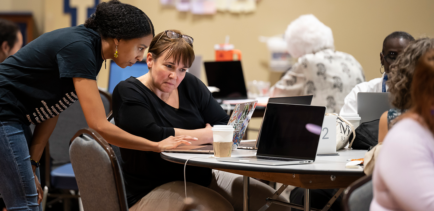 Two people looking at a computer during a RECI event