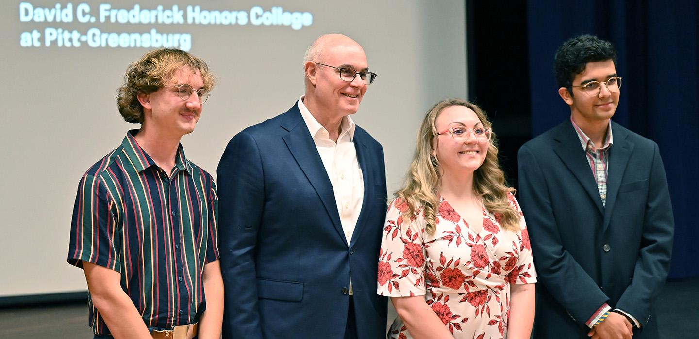 David Frederick stands with three honors students