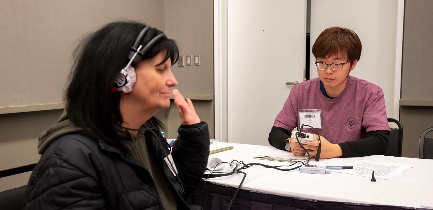 A person wears headphones and raises a hand during a hearing test