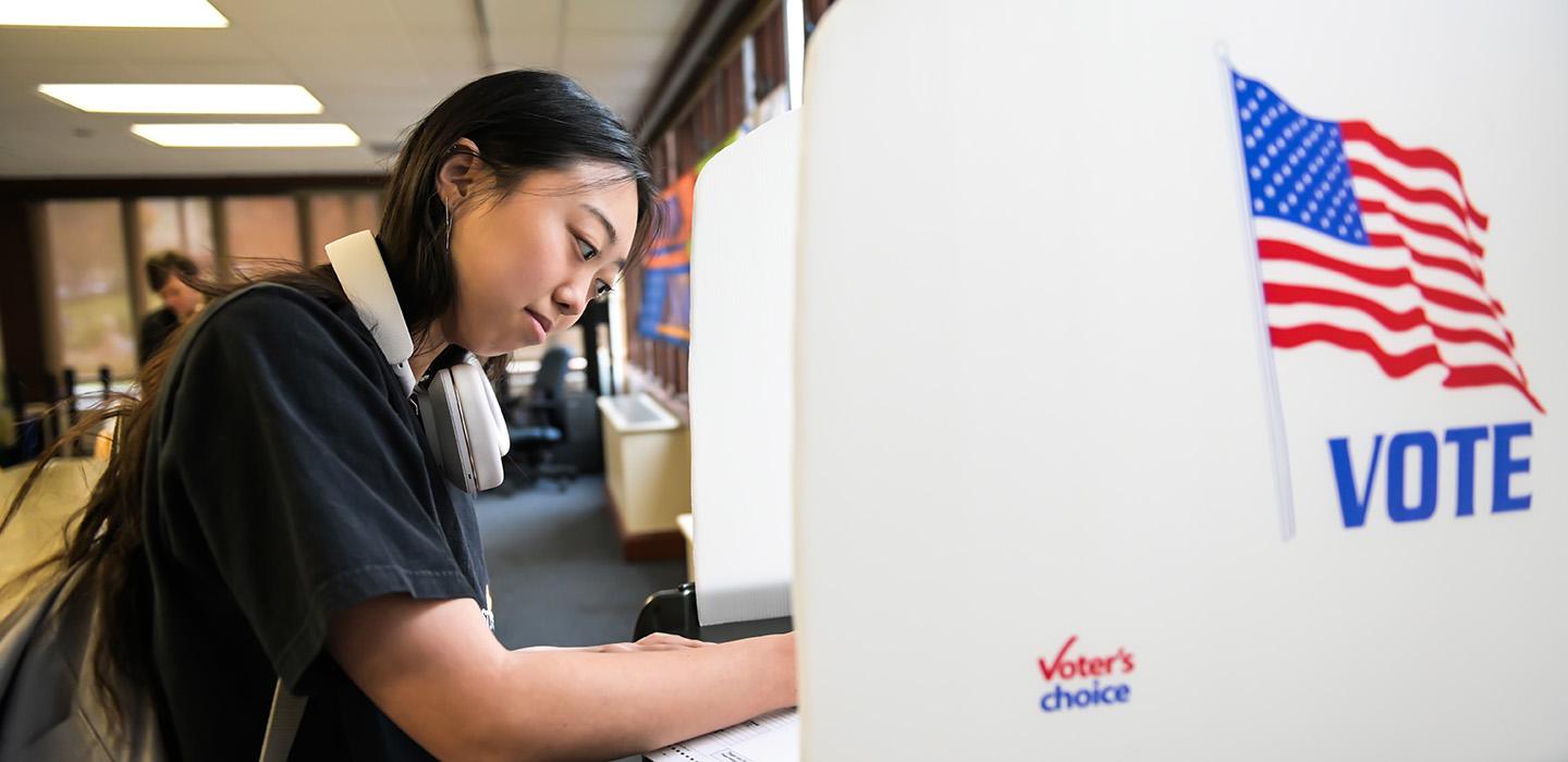 A student fills out a ballot at a mock voting booth