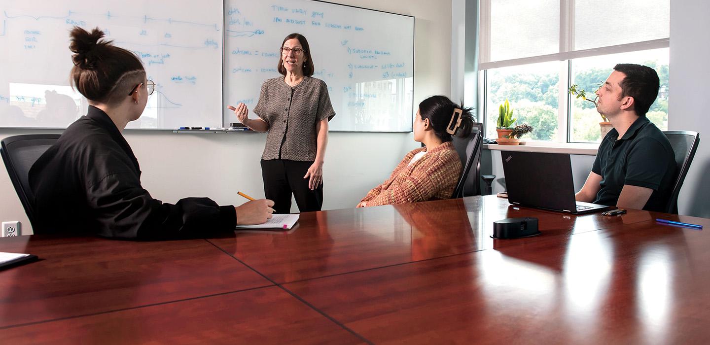 Maria Brooks talking to several people in front of a whiteboard
