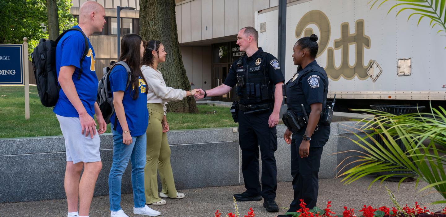 Public Safety police officer speak with and shake the hands of students.