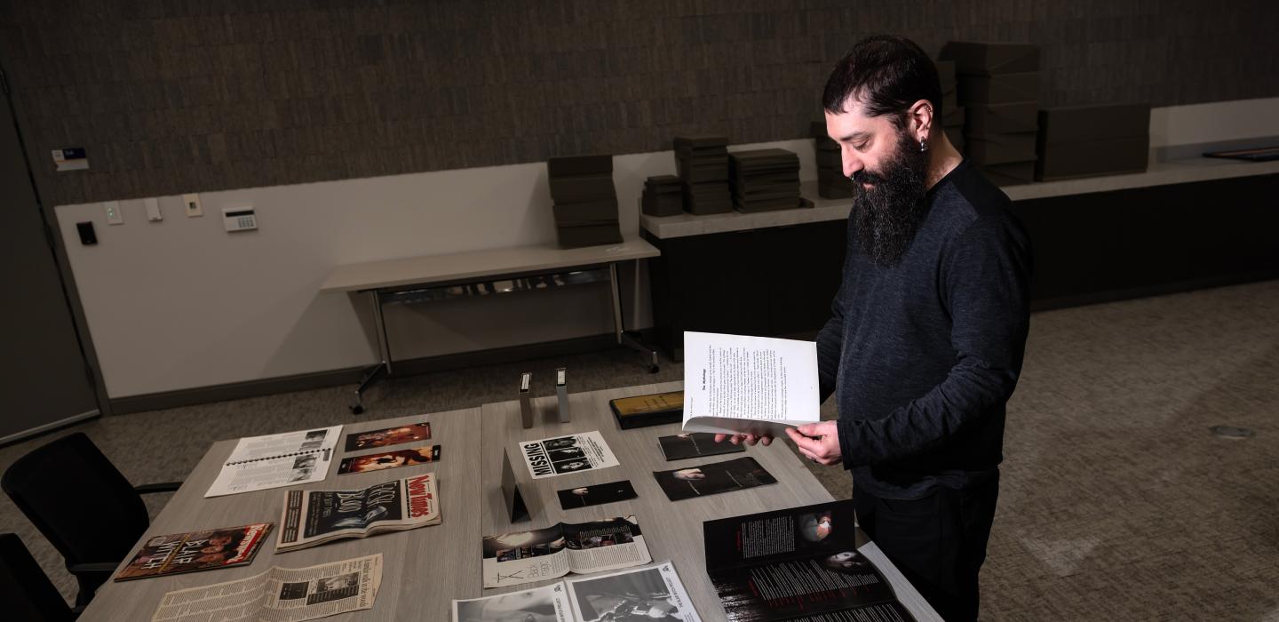 Rubin reads from a booklet while standing over a table of pamphlets and film props.