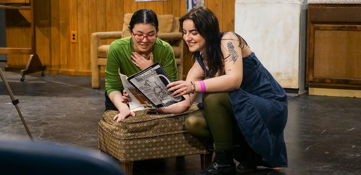 Two student actors look at a magazine