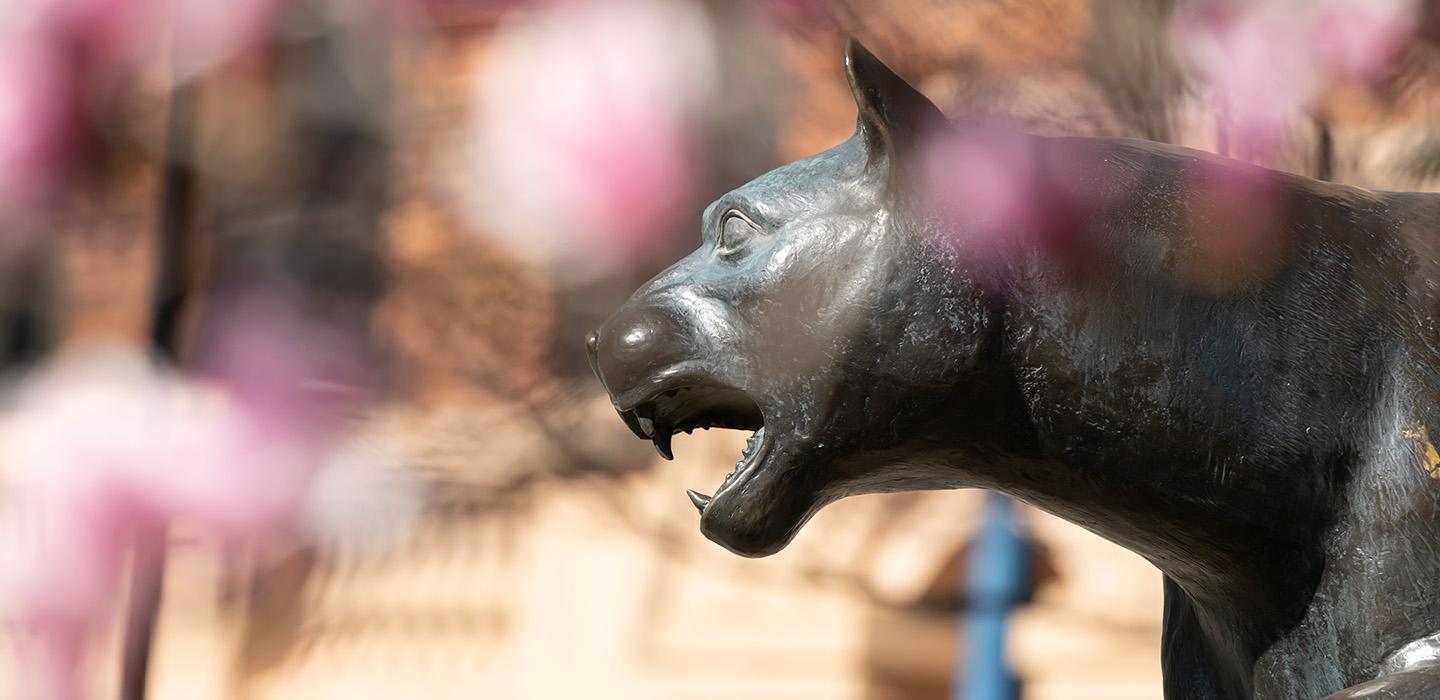 Panther statue with pink flowers in the foreground