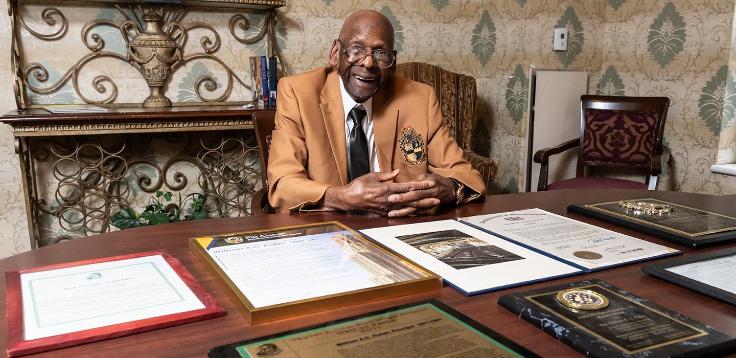 Fisher sits at a table, his awards spread before him.