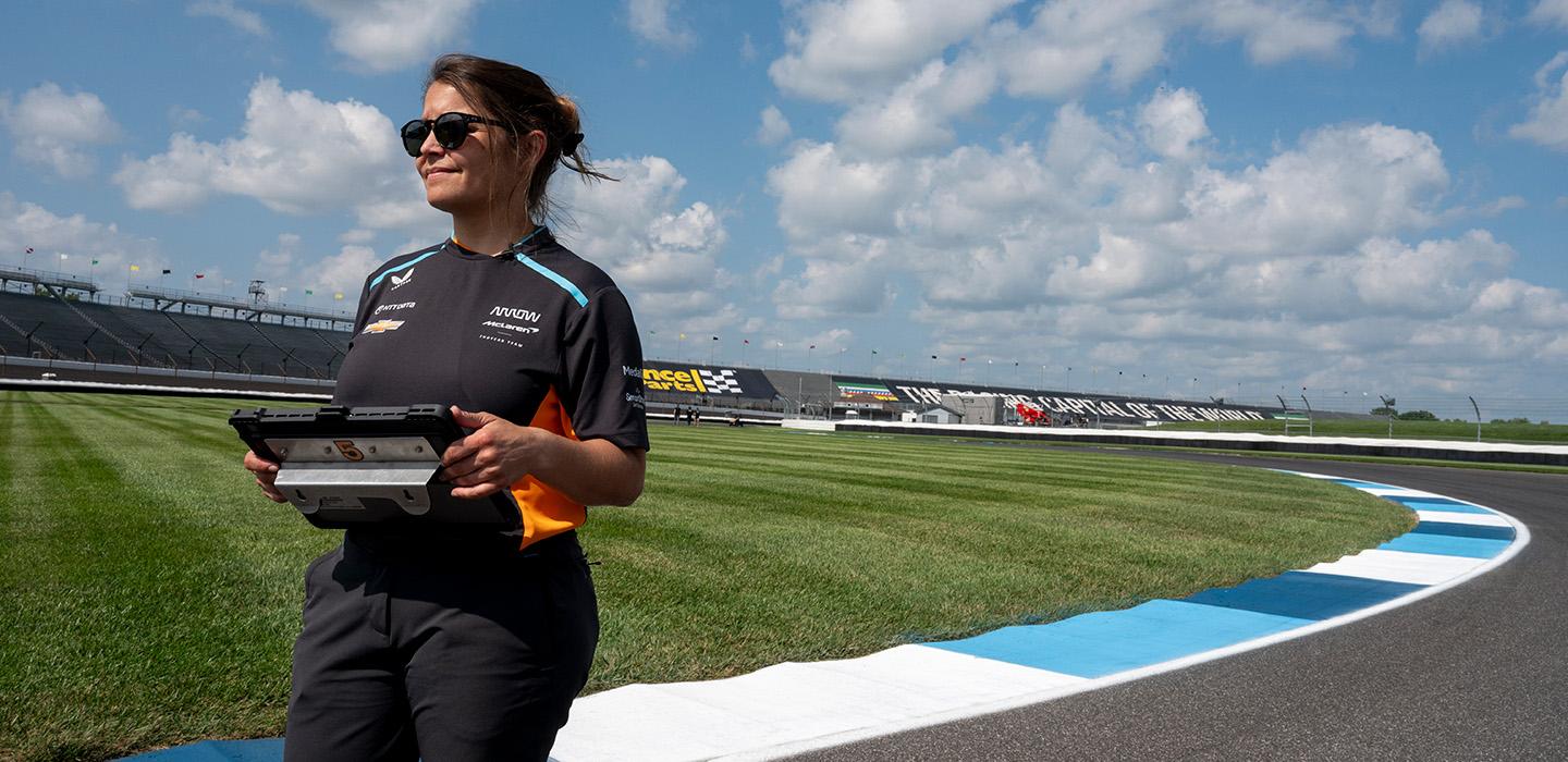Kate Gundlach stands on a racing car track on a lightly cloudy day