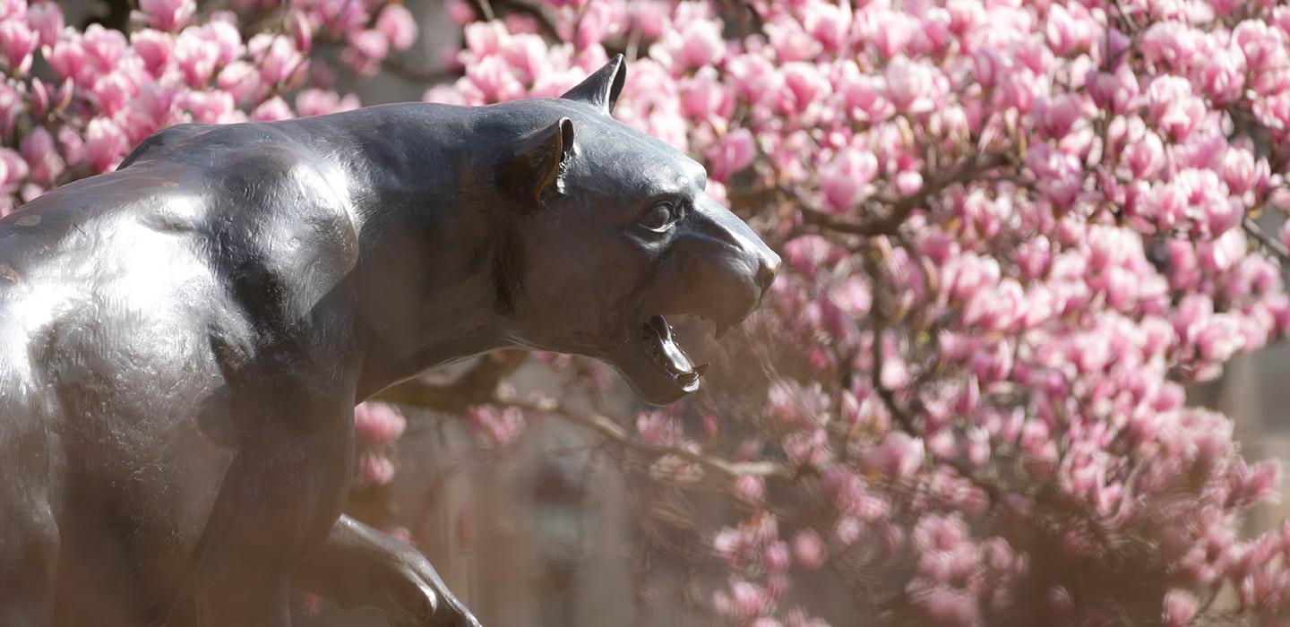A Panther statue surrounded by blooming trees.