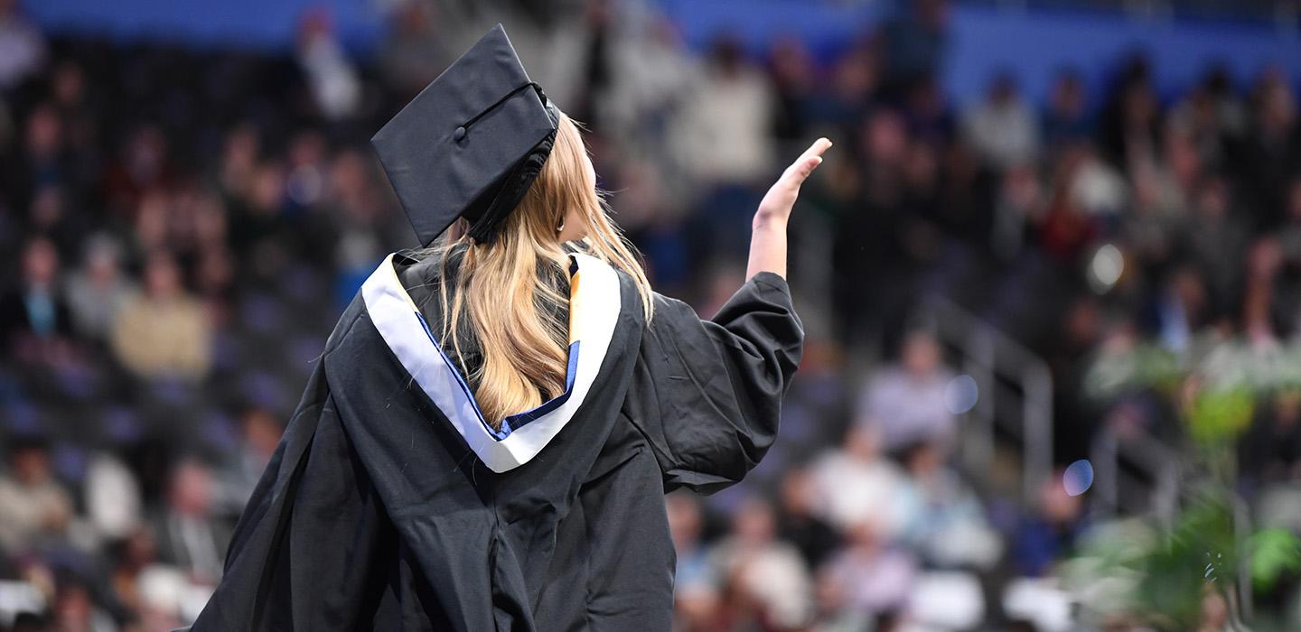 Student in graduation attire in front of a large audience