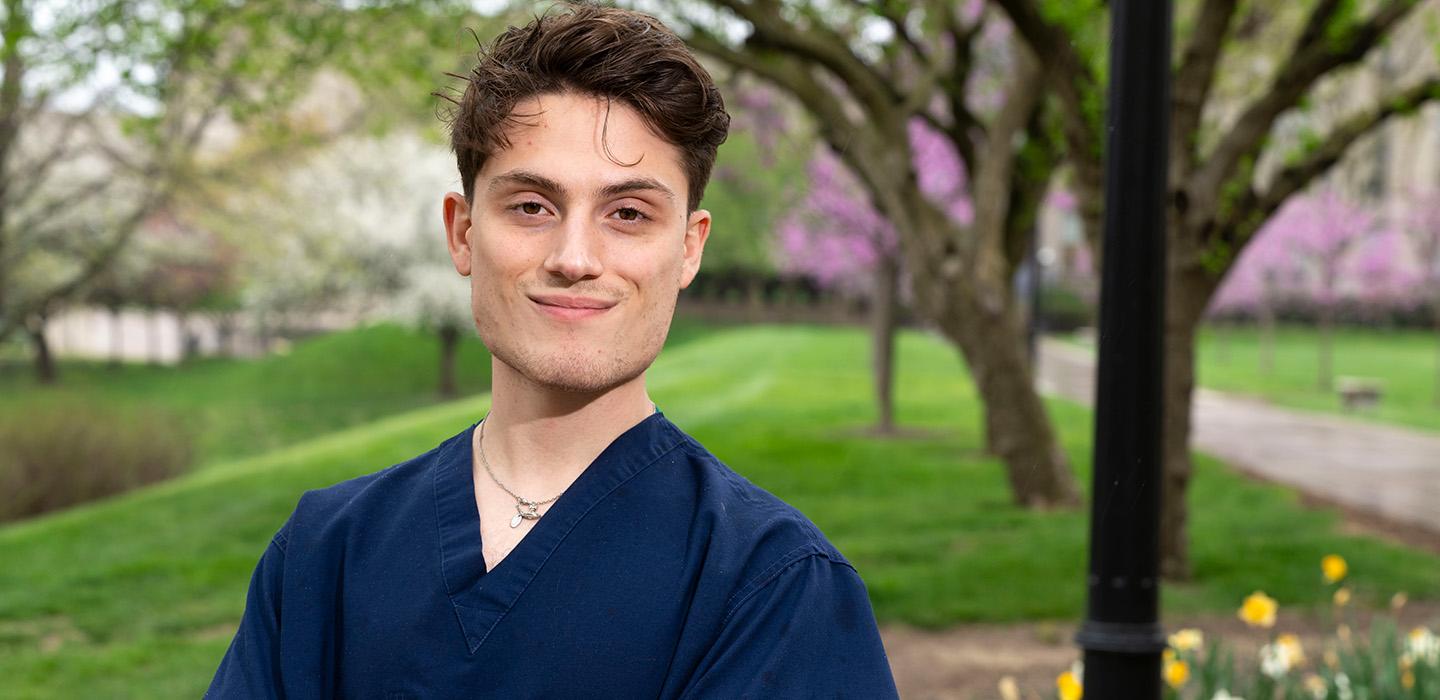 Joao Barichello posing in scrubs on Pitt's campus 