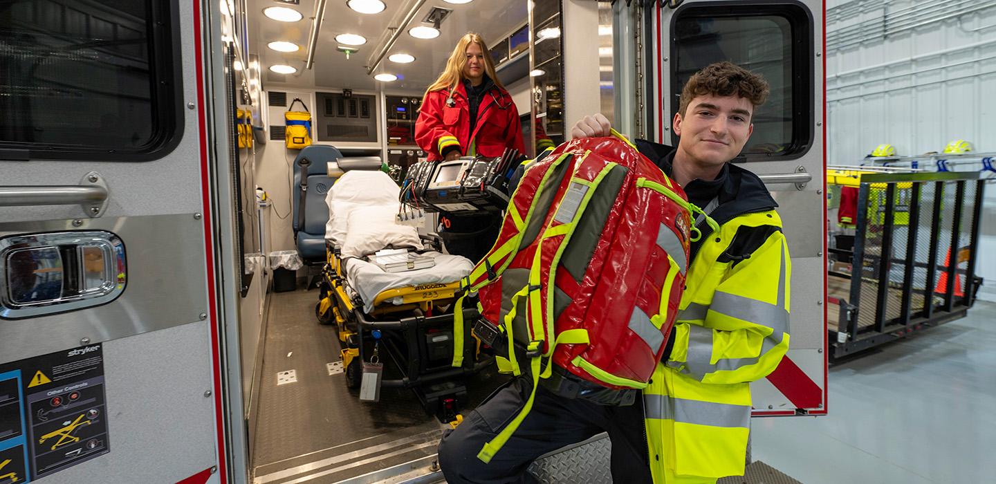 Two EMTs in an ambulance carrying emergency gear