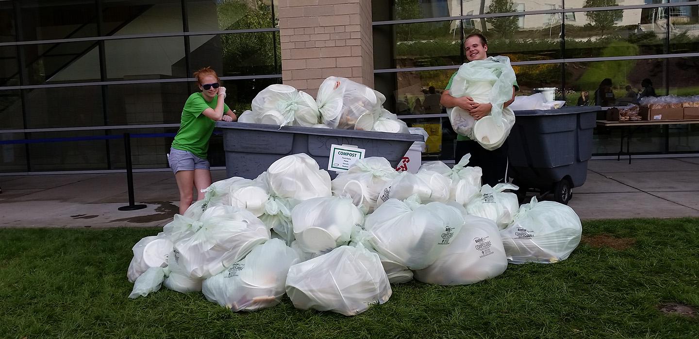 Two students posing with garbage bags