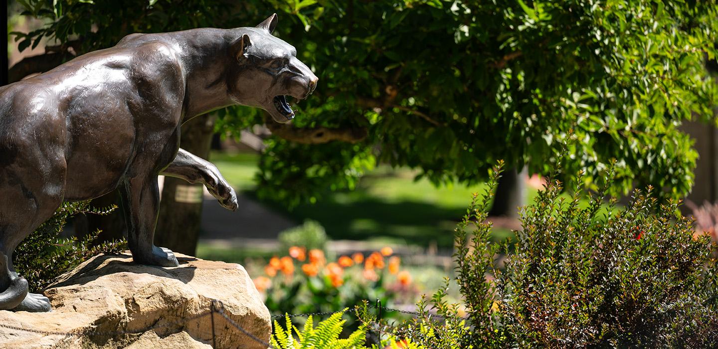 The panther statue surronded in summer foliage