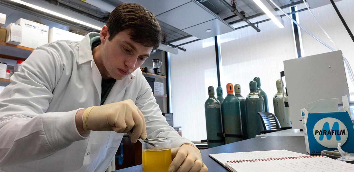 A student stirs a beaker in a lab.