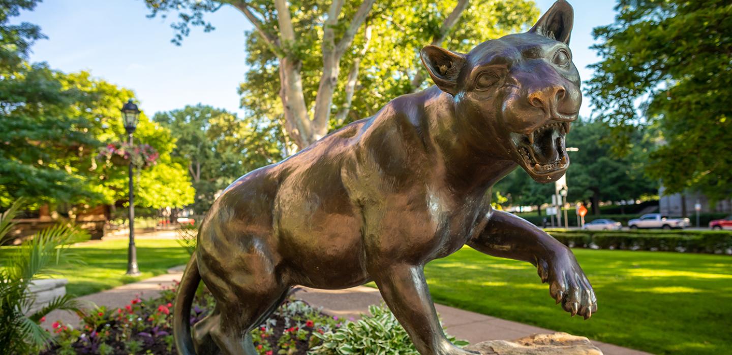 Bronze Panther statue with red flowers at its base
