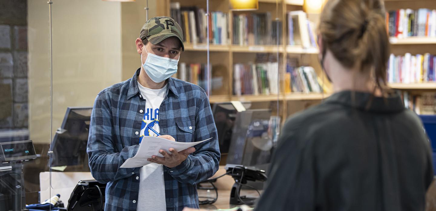 A person in a blue shirt writes on a piece of paper