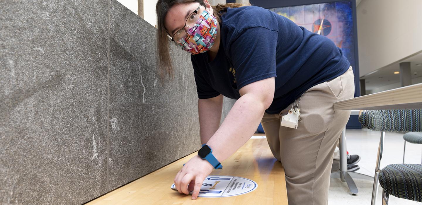 Kaila Mauro installs a reminder sticker on a bench
