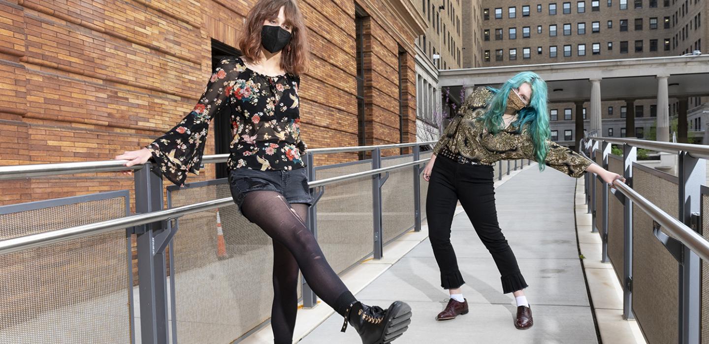 Margaret Balich on the left and Stacy Cremer on the right both lean against railing on a walkway