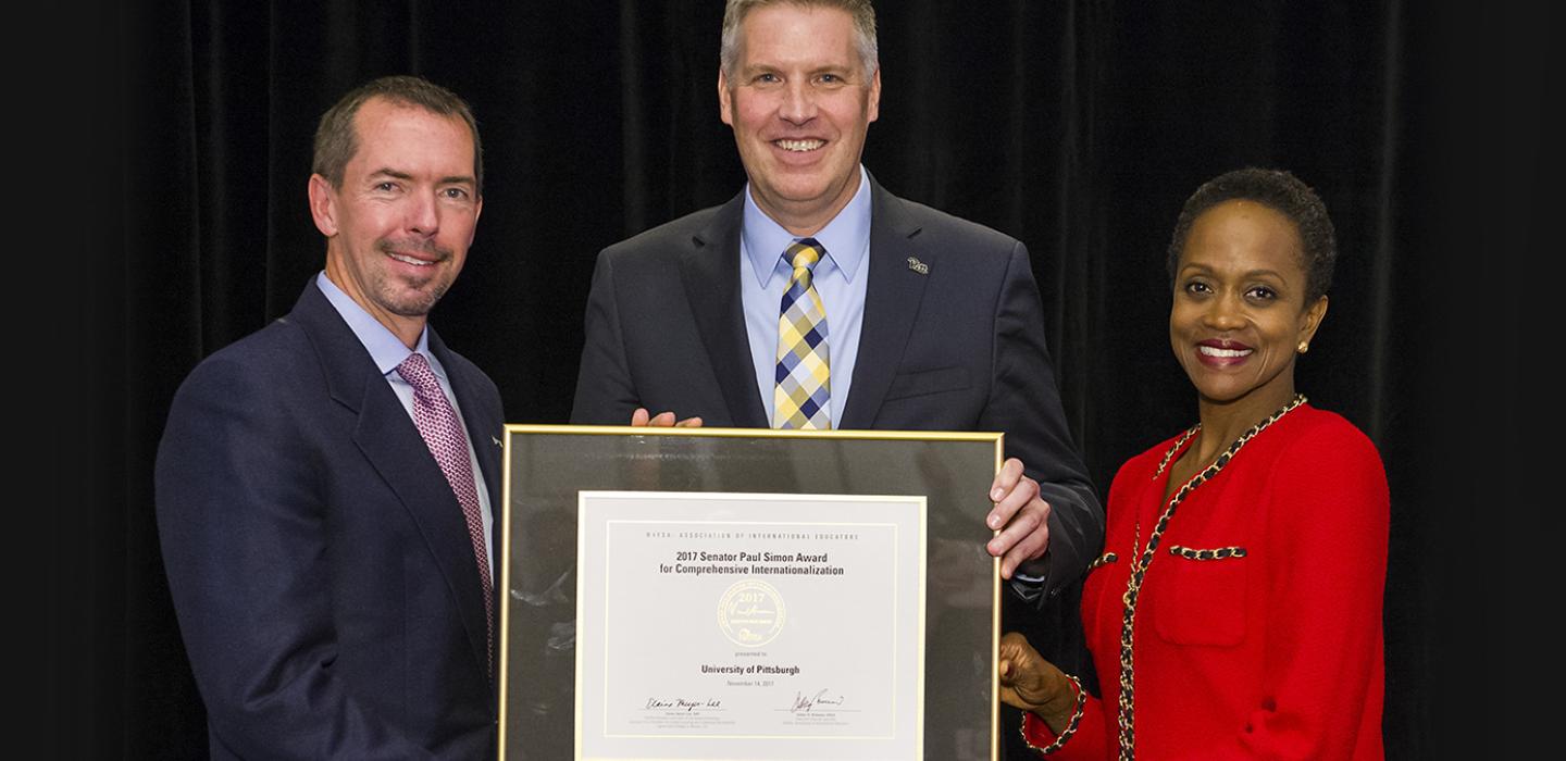Chancellor Patrick Gallagher accepting award from two presenters