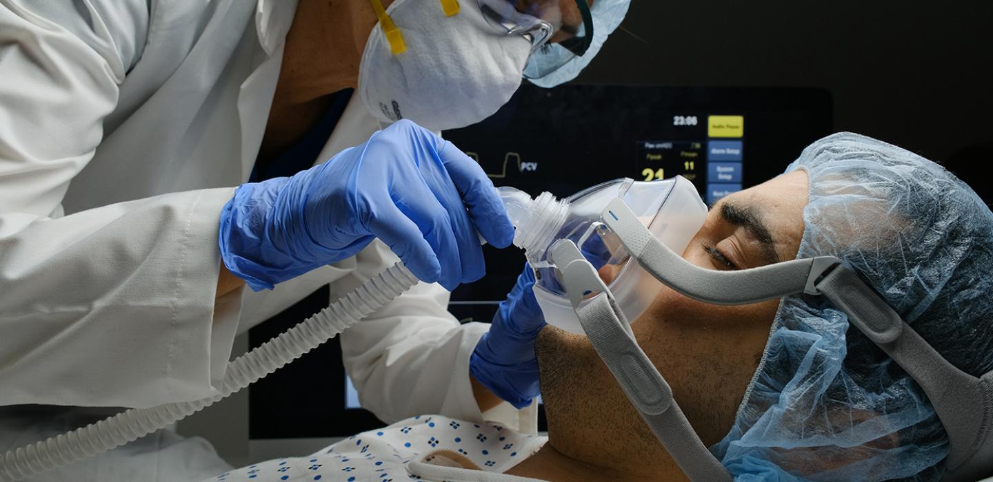 a doctor placing an oxygen mask on a patient in a bed