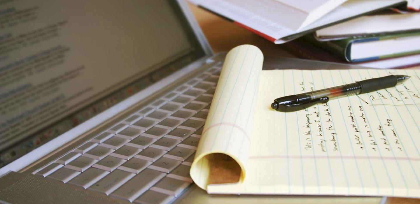 a notebook and pen on top of a laptop keyboard
