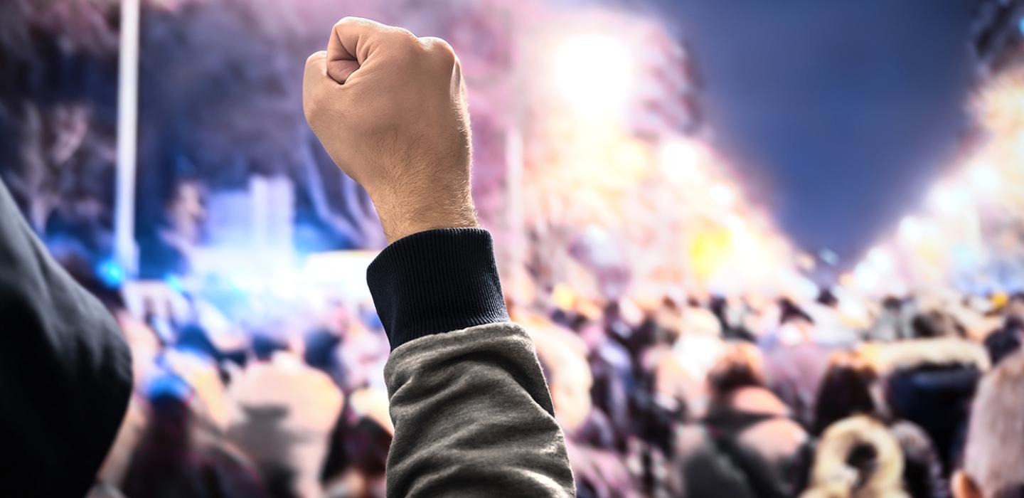 A raised fist in the air in a crowd of people on a city street