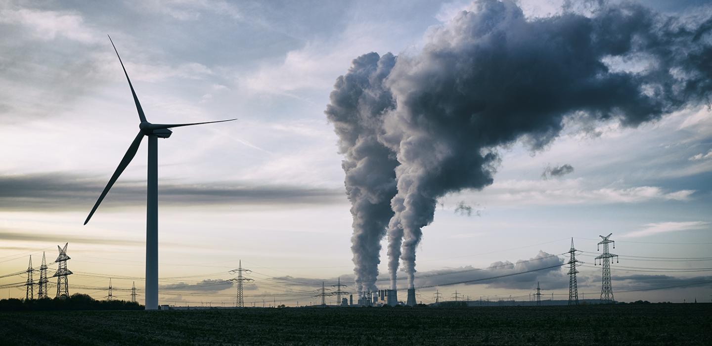 A wind turbine and smokestacks
