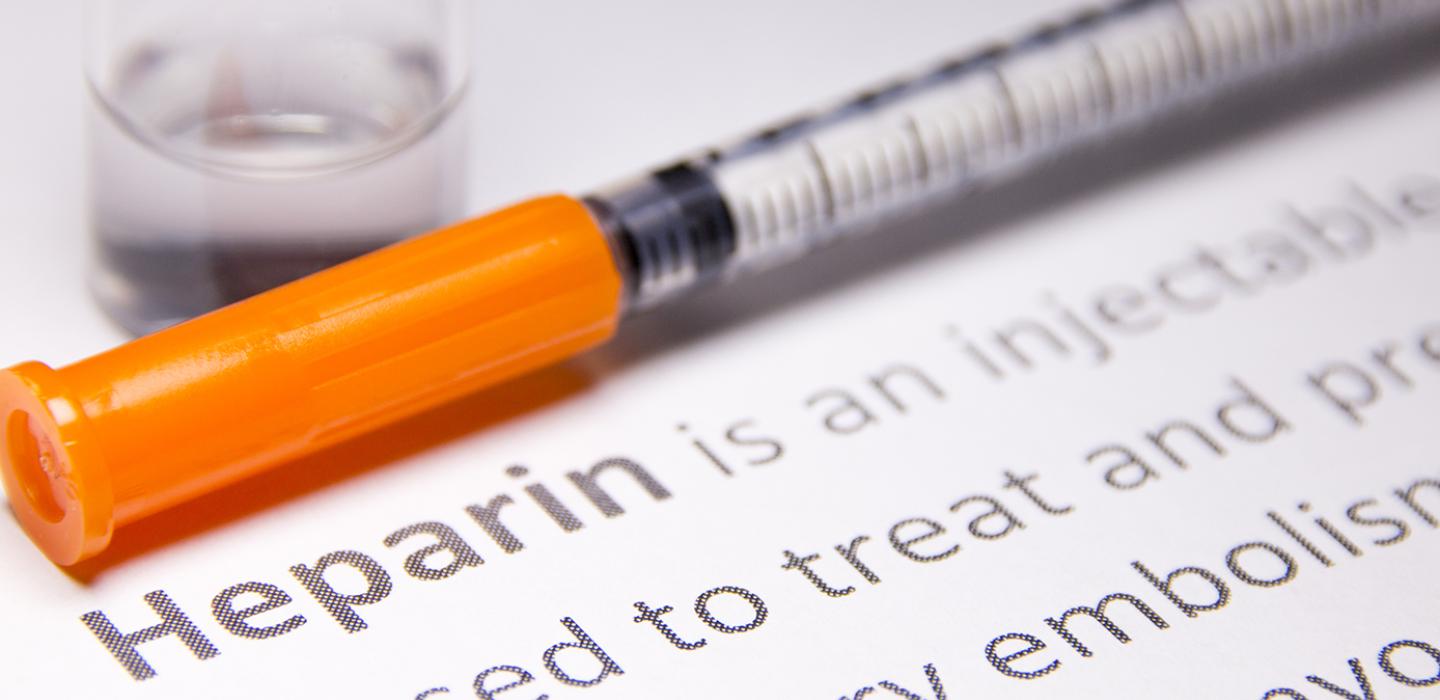 A bottle of medicine next to an orange-capped syringe