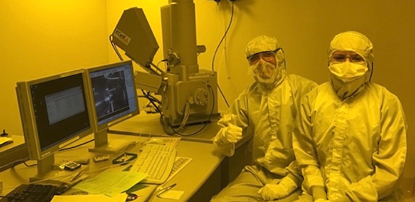 Emily and her mentor in full-body protective suits in front of a computer