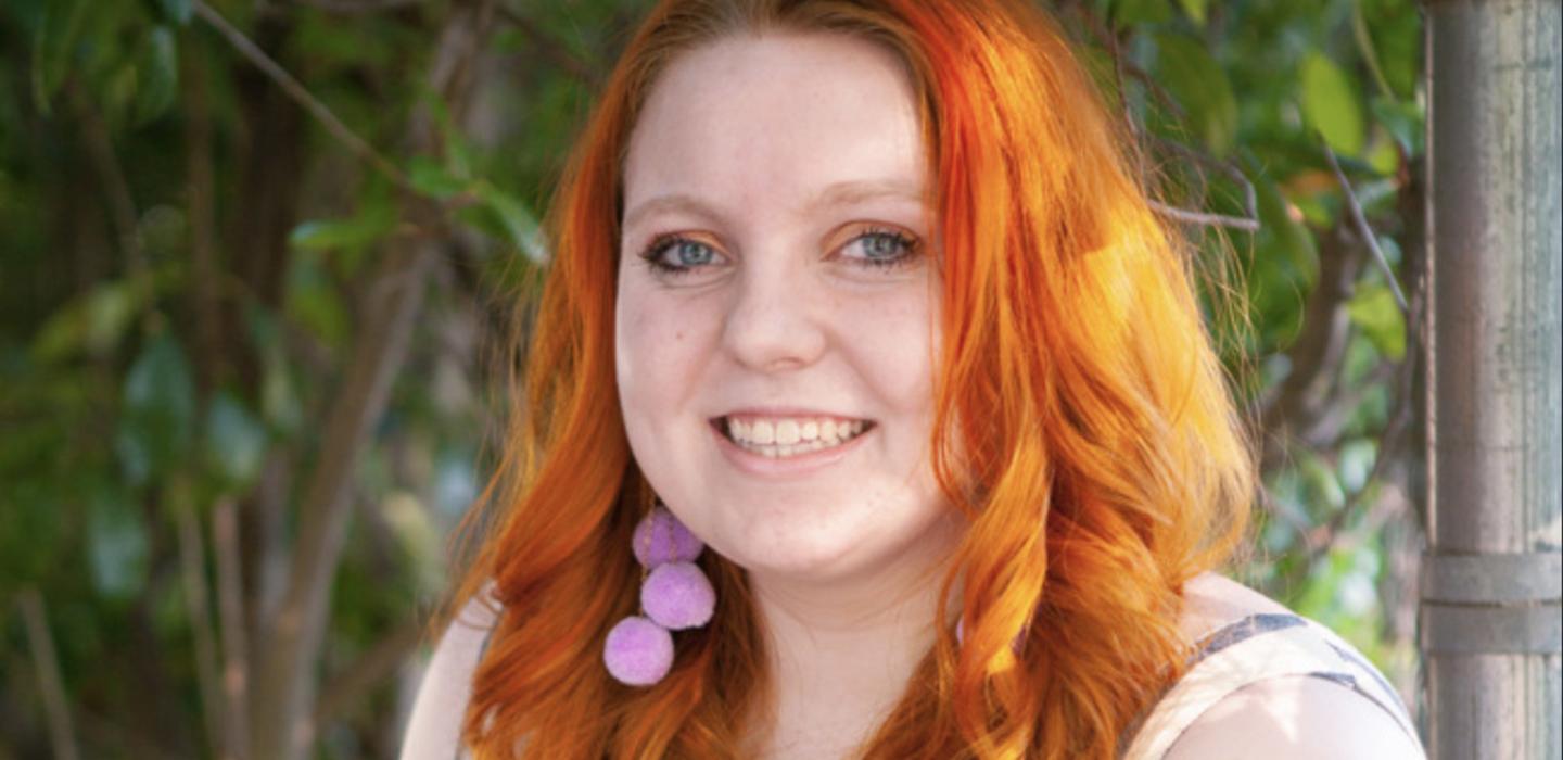A woman with pink earrings and a light top
