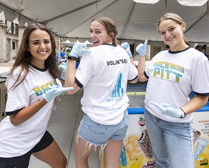 Three Pitt sophomores volunteering handing out refreshments