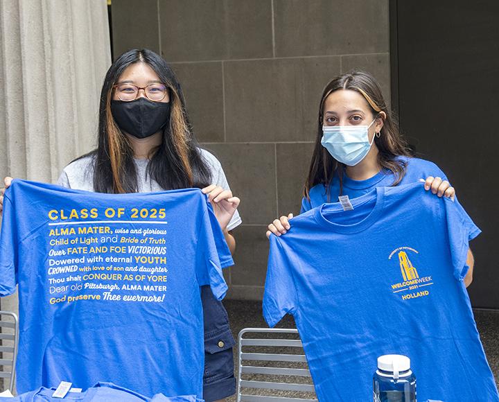 Two Pitt students holding blue Class of 2025 shirts