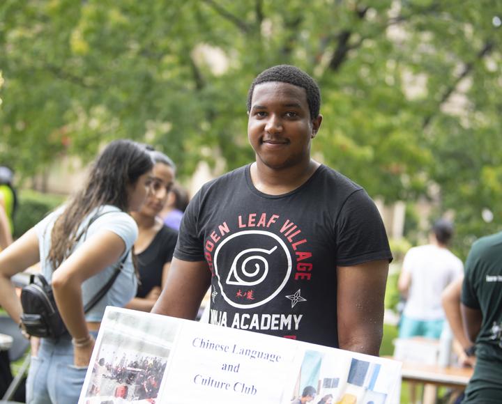 Man in black shirt smiling, holding sign