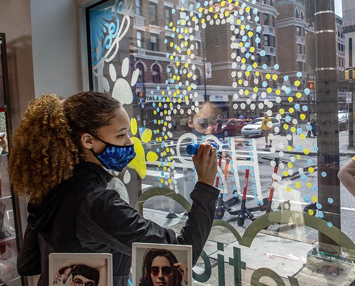 Carsyn Campbell decorating window with markers.