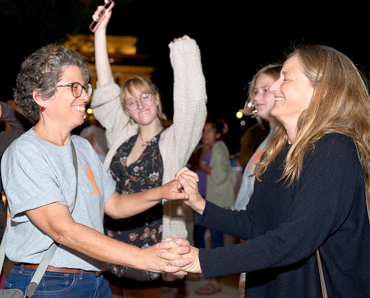Women holding hands and dancing together at festival