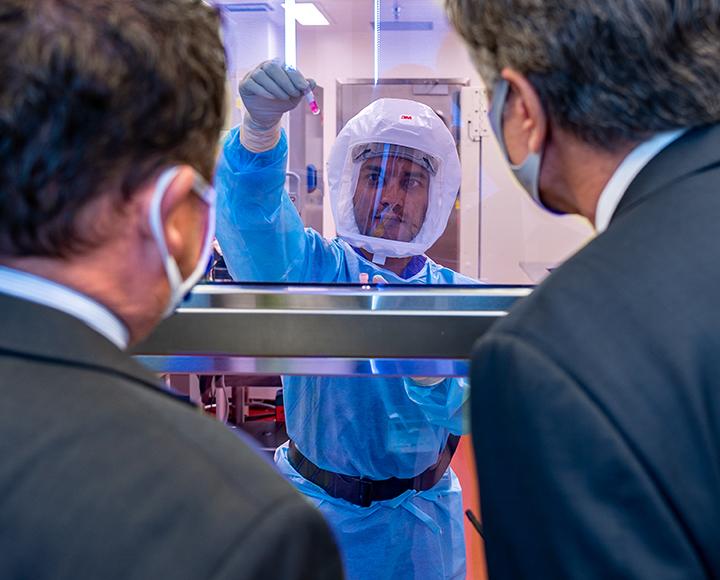 Sham Nambulli speaking with Antony Blinken through opposite side of glass from lab