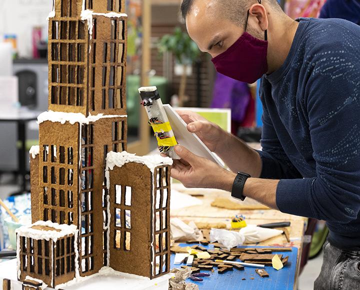 Man with face mask installing lights to gingerbread Cathedral of Learning