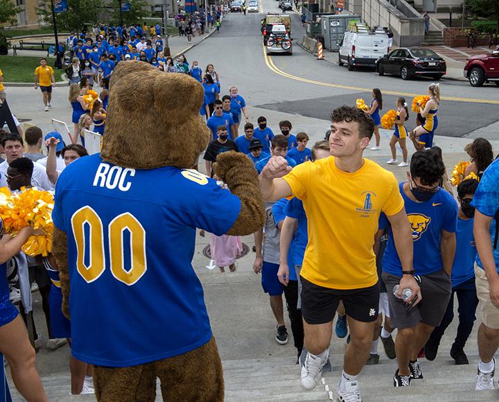 Roc greeting a student with a fist bump as they enter the Petersen Events Center